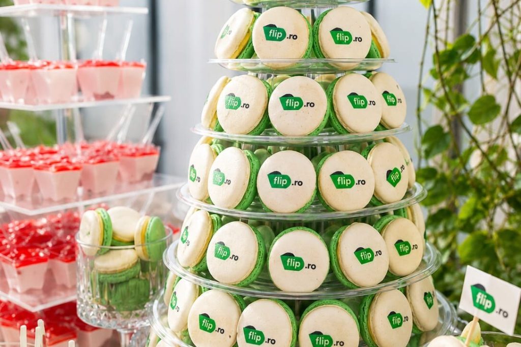Turn de macarons imprimați cu logo-ul flip.ro, alături de verrine roz și roșii, la un candy bar corporate