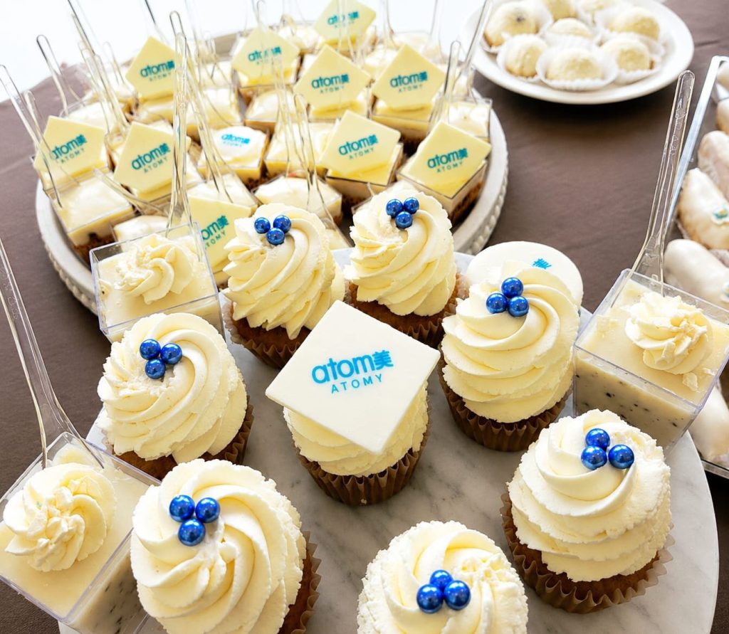 Candy bar corporate cu cupcakes și prăjituri personalizate cu logo-ul Atomy imprimat pe ciocolată albă