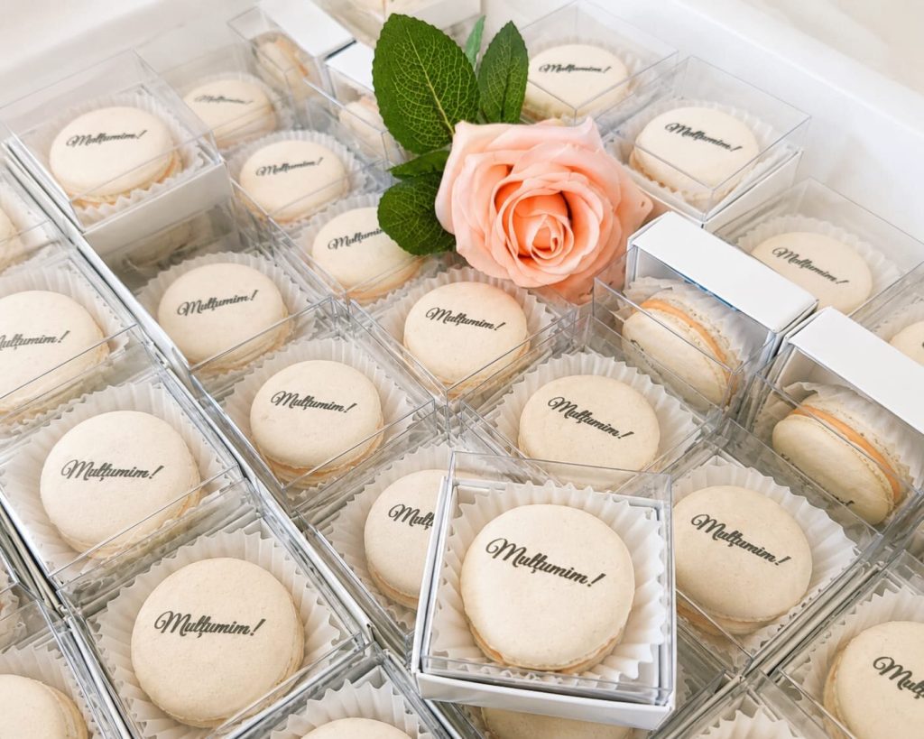 Macarons personalizați cu mesajul „Mulțumim!”, ambalați individual în cutiuțe transparente, oferiți ca mărturii de nuntă